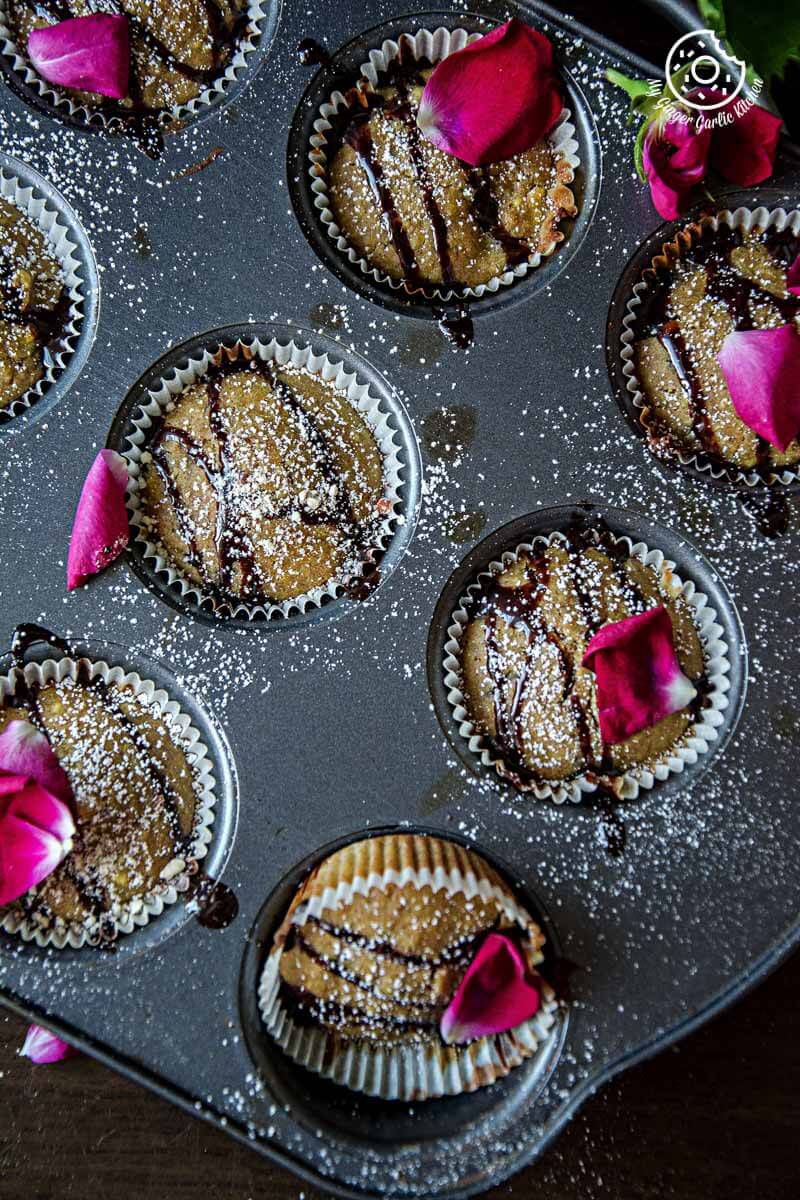 a bunch of oats orange eggless muffins in a muffin tin with flowers