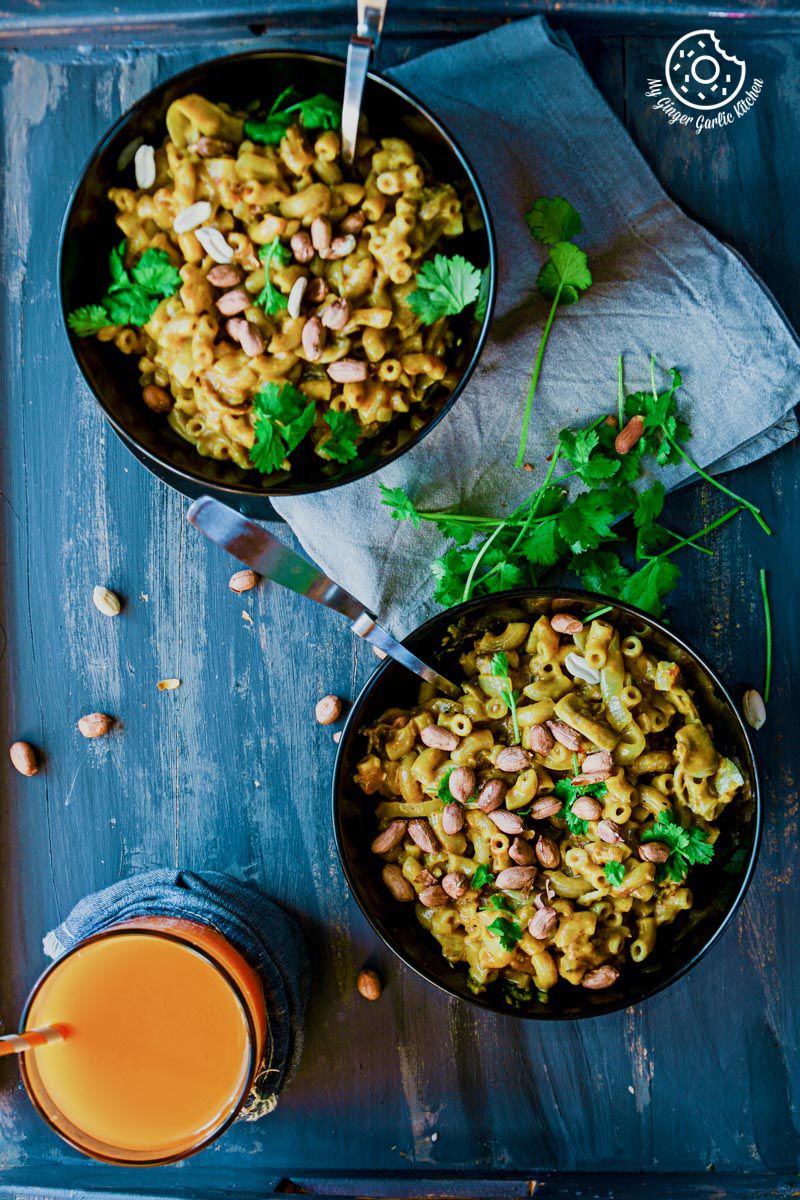 two bowls of one pan thai yellow curry mac and parsley on a tray