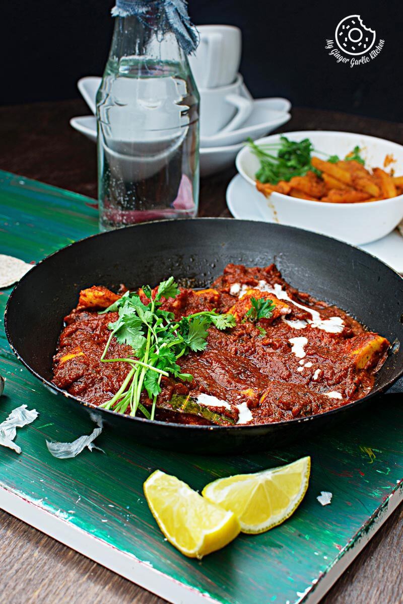 a pan of paneer butter masala on a table with a lemon wedge