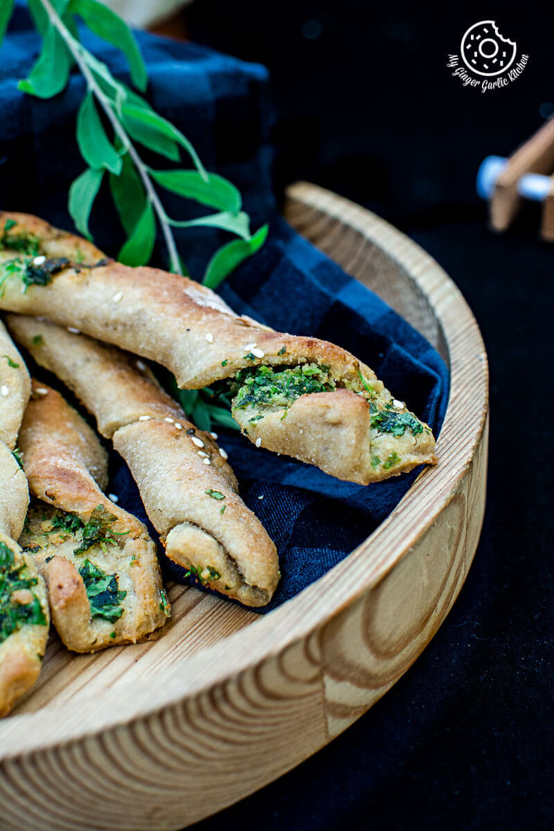 pizza dough twists with parsley with some leaves on a wooden plate