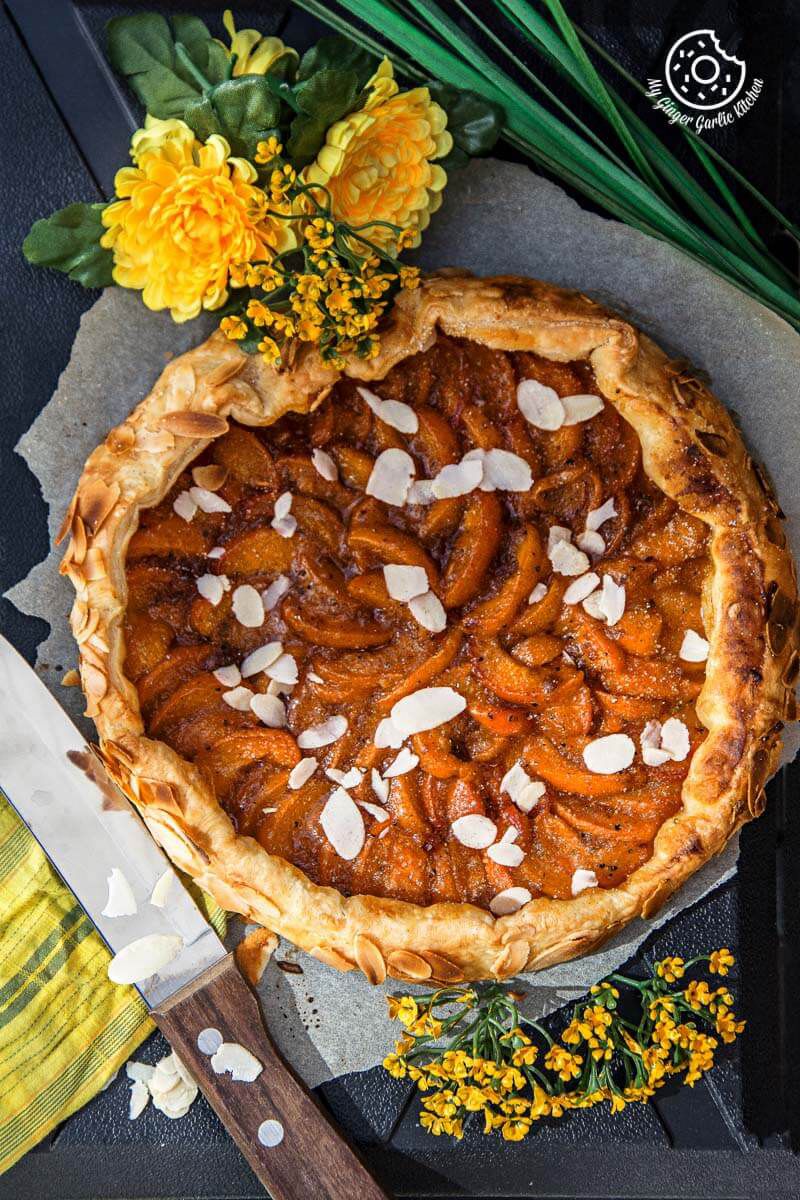 a puff pastry apricot galette with almond toppings on a table