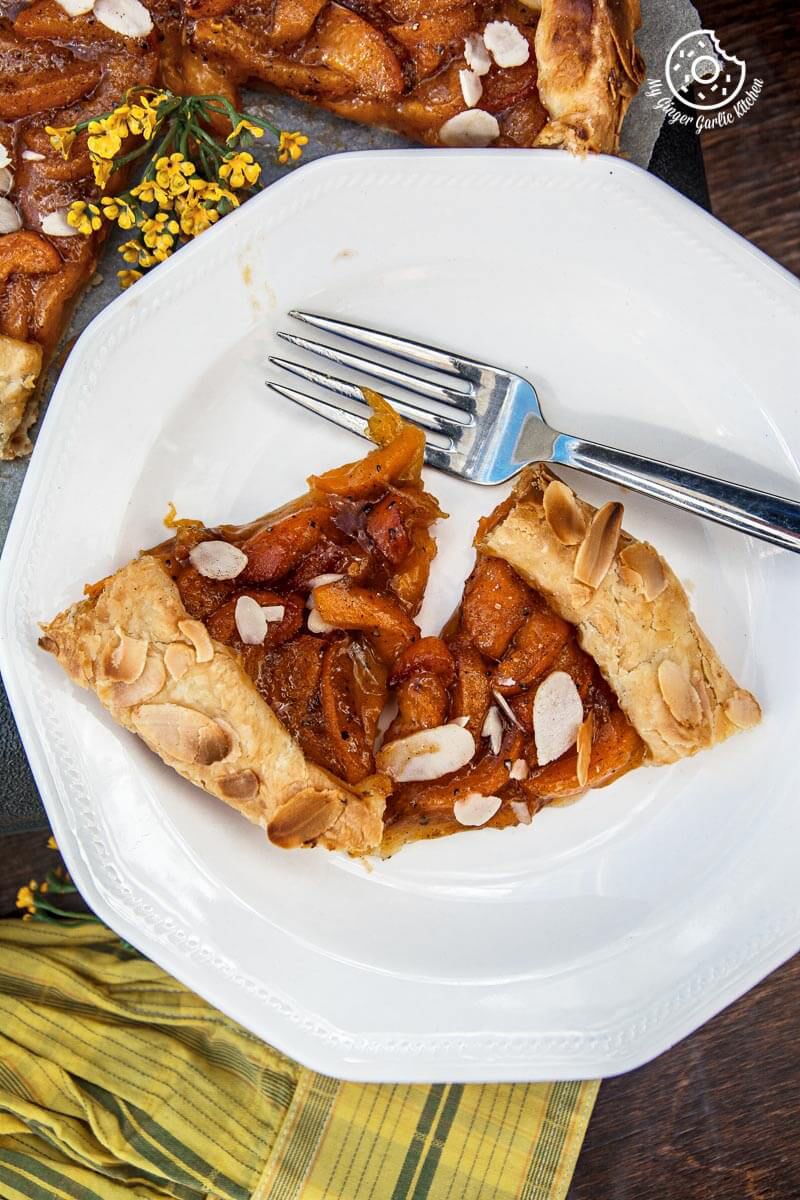 a piece of puff pastry apricot galette with almond topping on a plate with a fork