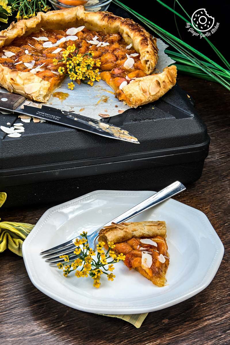 a piece of puff pastry apricot galette with almond topping on a plate with a fork