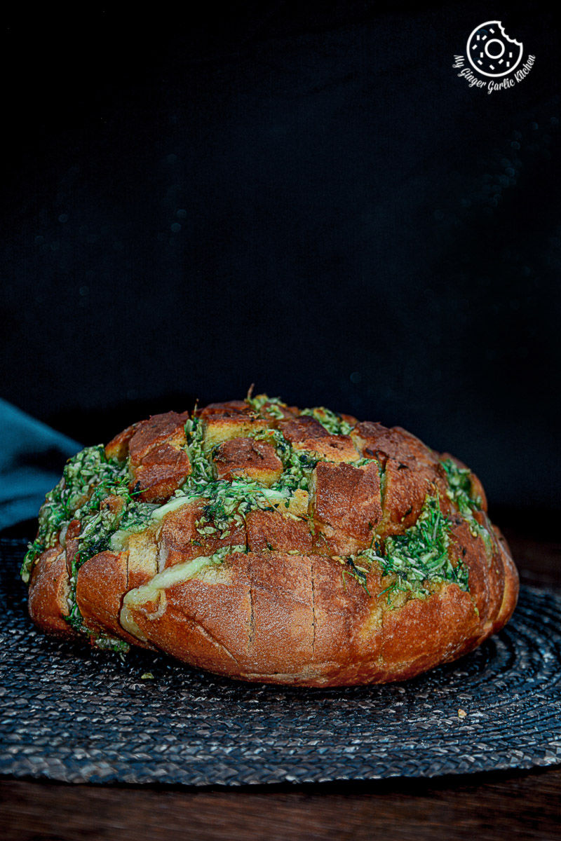 a loaf of pull apart garlic parsley bread on a plate