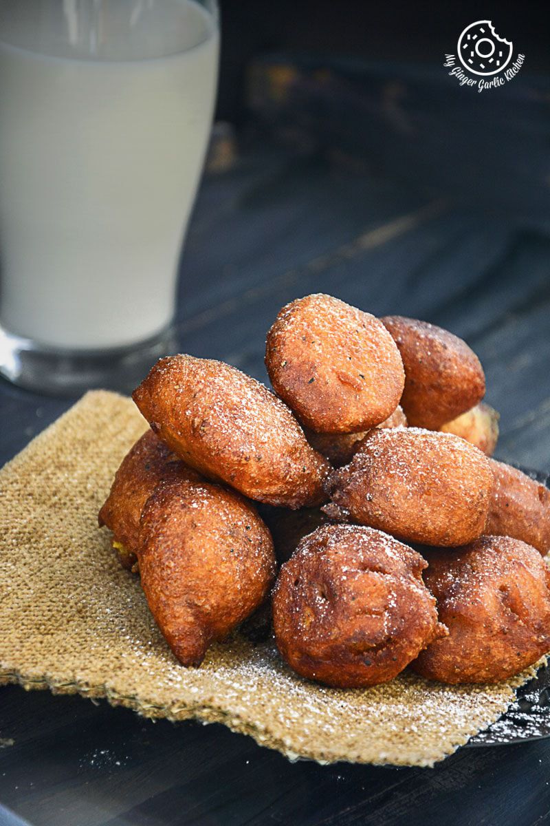 a bunch of fried pumpkin fritters on a napkin next to a glass of milk