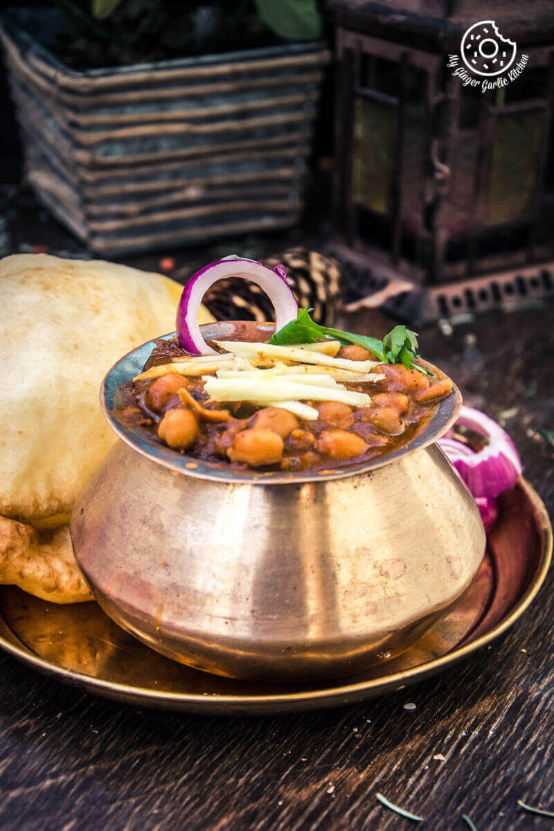 there is a bowl of chole on a plate with fried bhatura