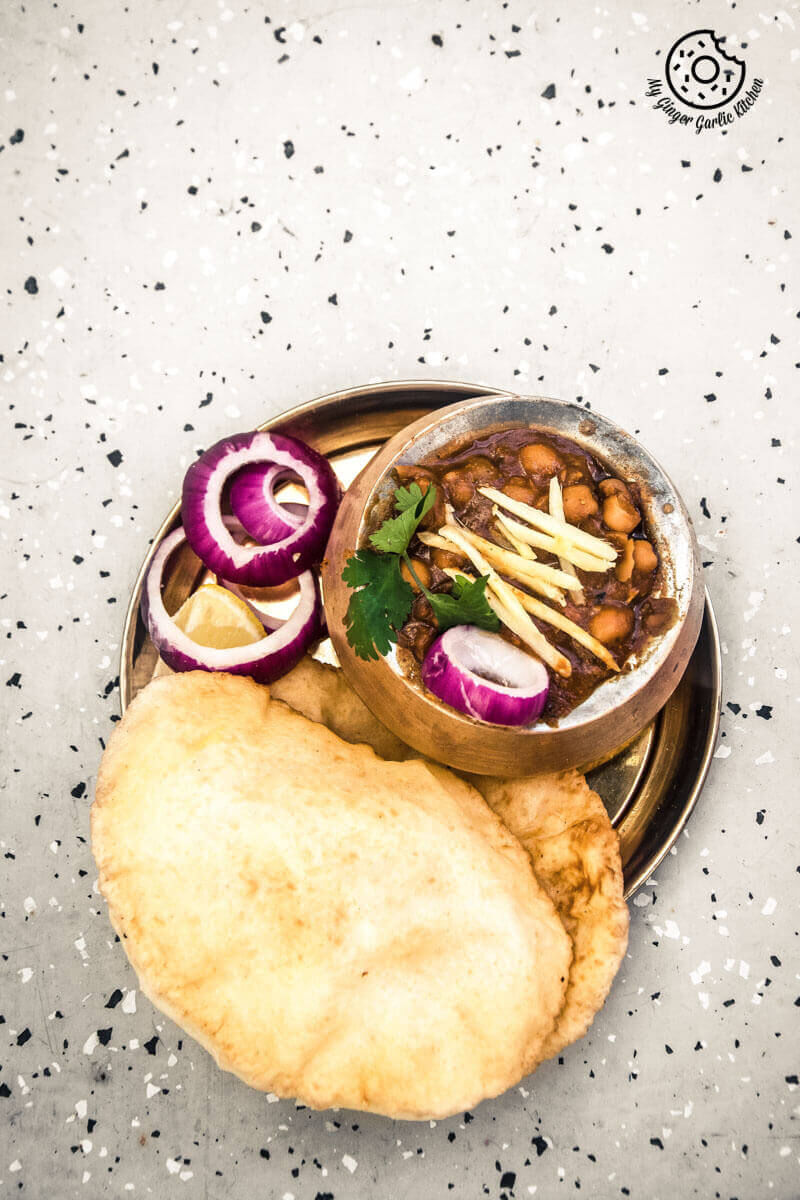 there is a plate of chole bhature with onion slices