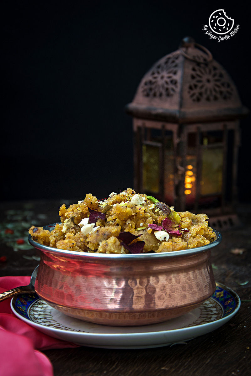 a bowl of rajasthani moong dal halwa on a plate with a lantern in the background