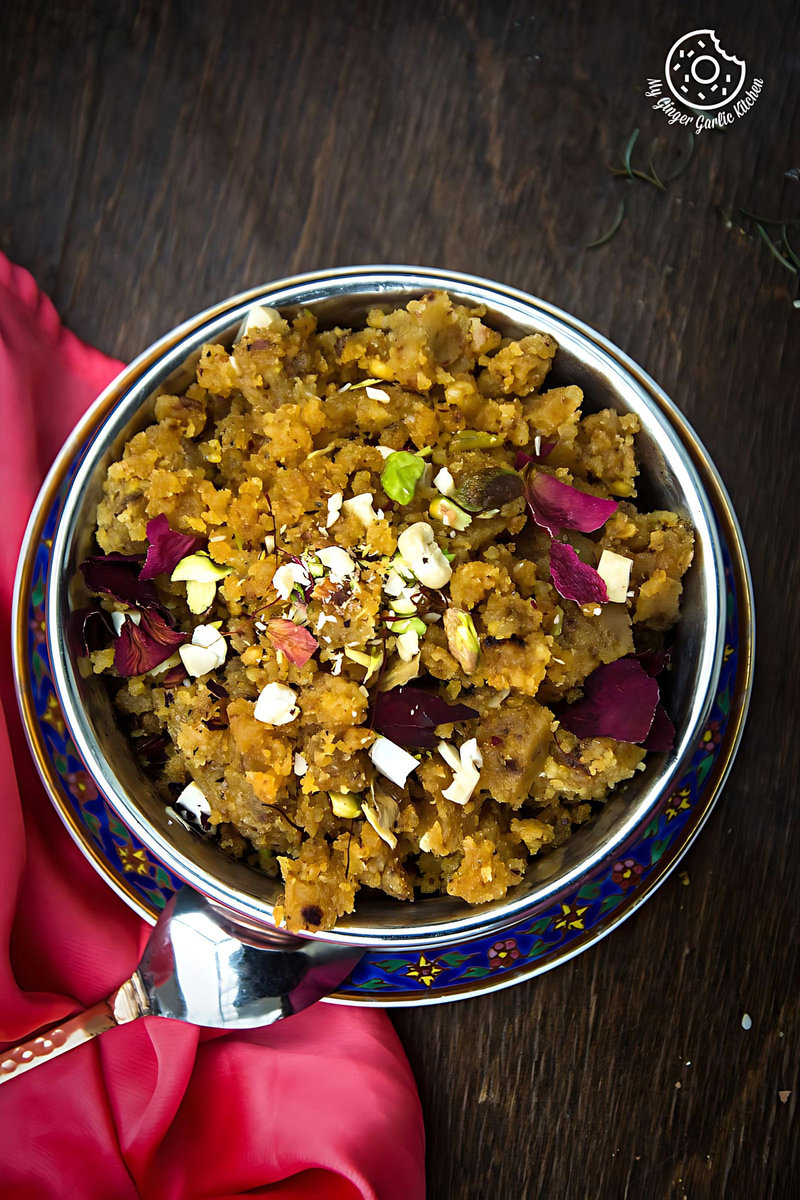 a bowl of rajasthani moong dal halwa garnished with nuts and a napkin