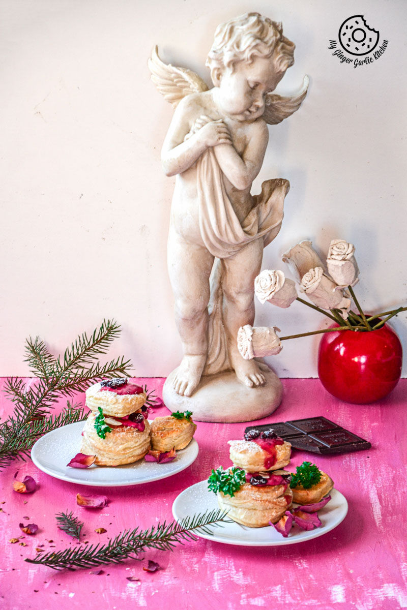 two plates of raspberry creme fraiche and cookies puffs on a table with a statue