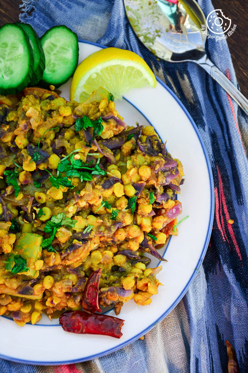 a plate of red cabbage zucchini chana dal with a lemon and cucumber on it