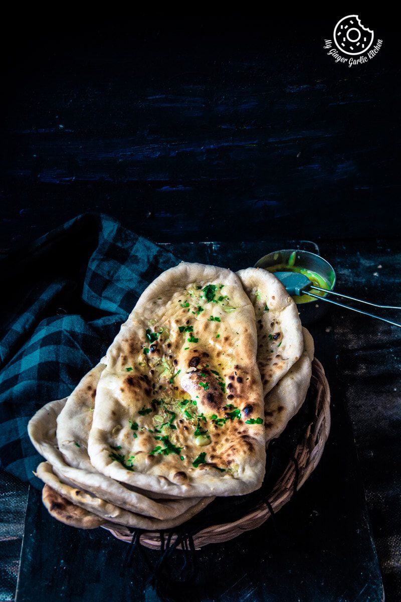 a stack of Restaurant Style Indian Garlic Naan with a ghee bowl on the side