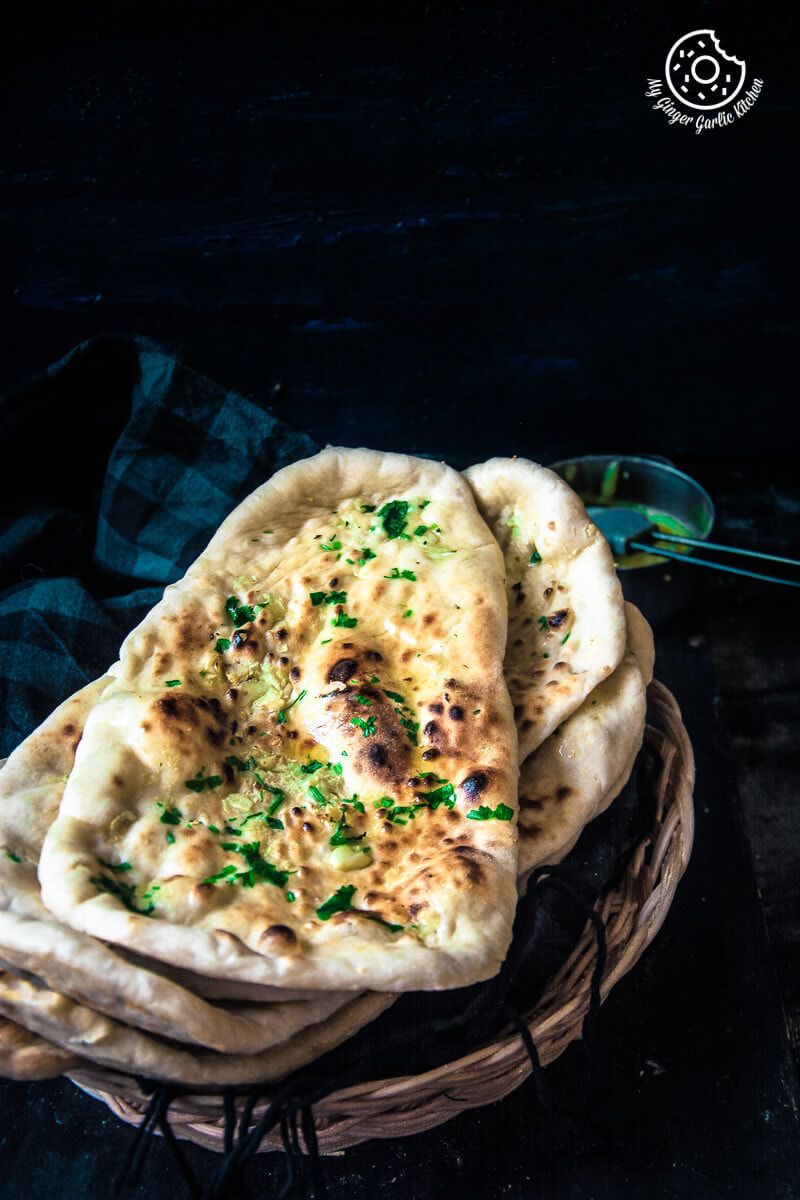 a stack of Restaurant Style Indian Garlic Naan with a ghee bowl on the side