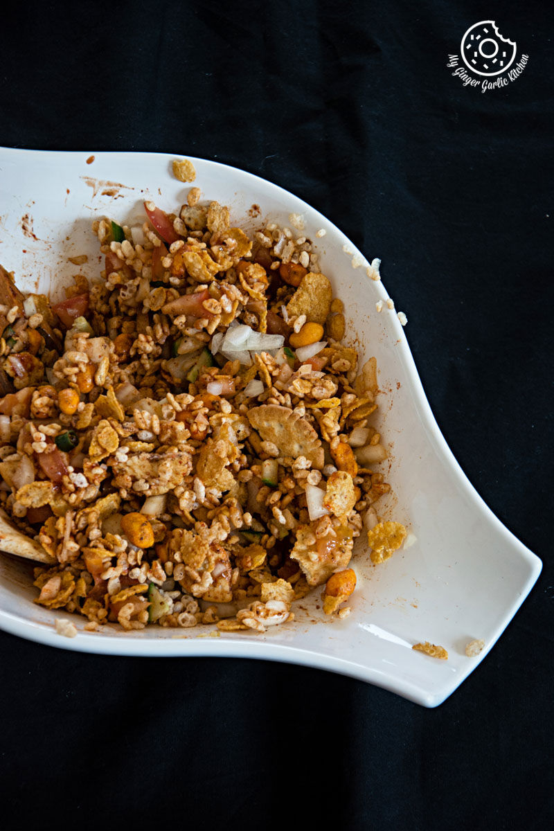 a white bowl filled with rice krispie cornflakes bhel on a black table
