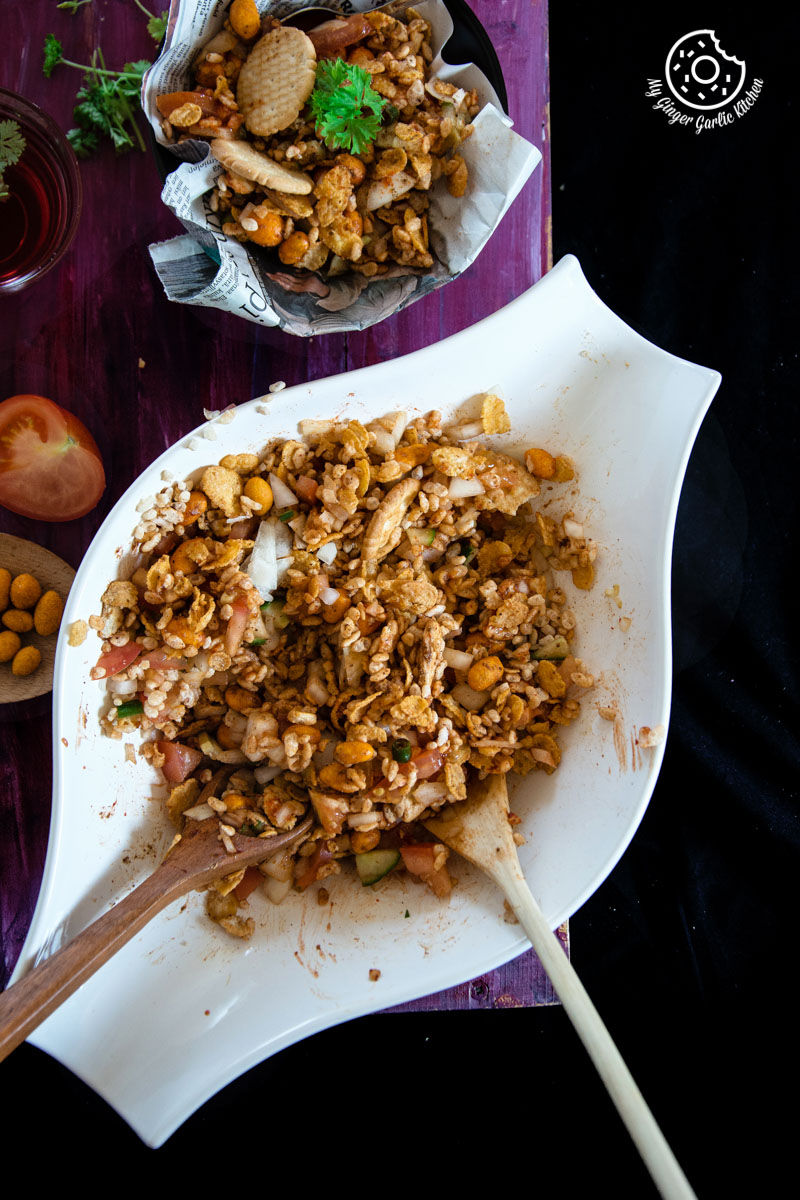 a plate of rice krispie cornflakes bhel with a spoon and a bowl of food