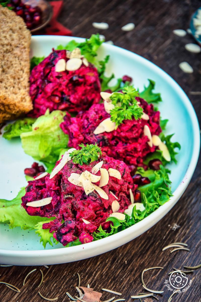 a plate of roasted beet potato holiday salad with bread on it