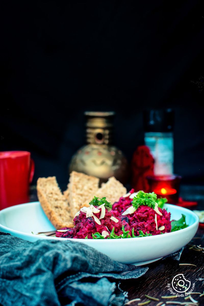 a bowl of roasted beet potato holiday salad with bread and a drink