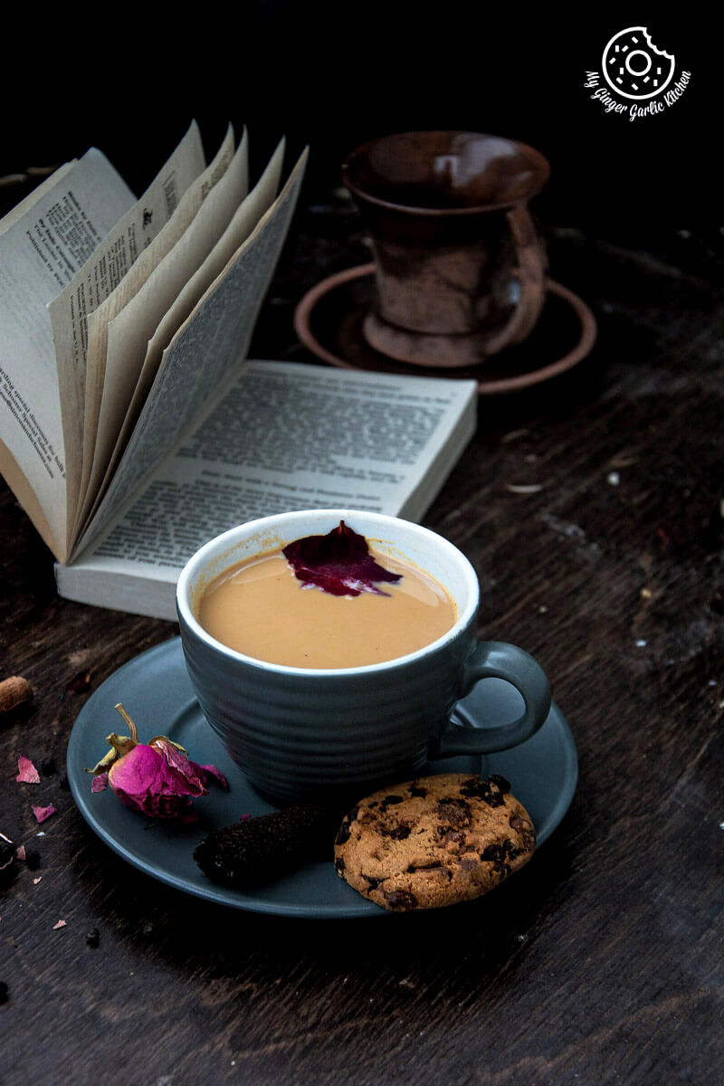 a cup of rose masala chai and a chocolate chip cookie on a table