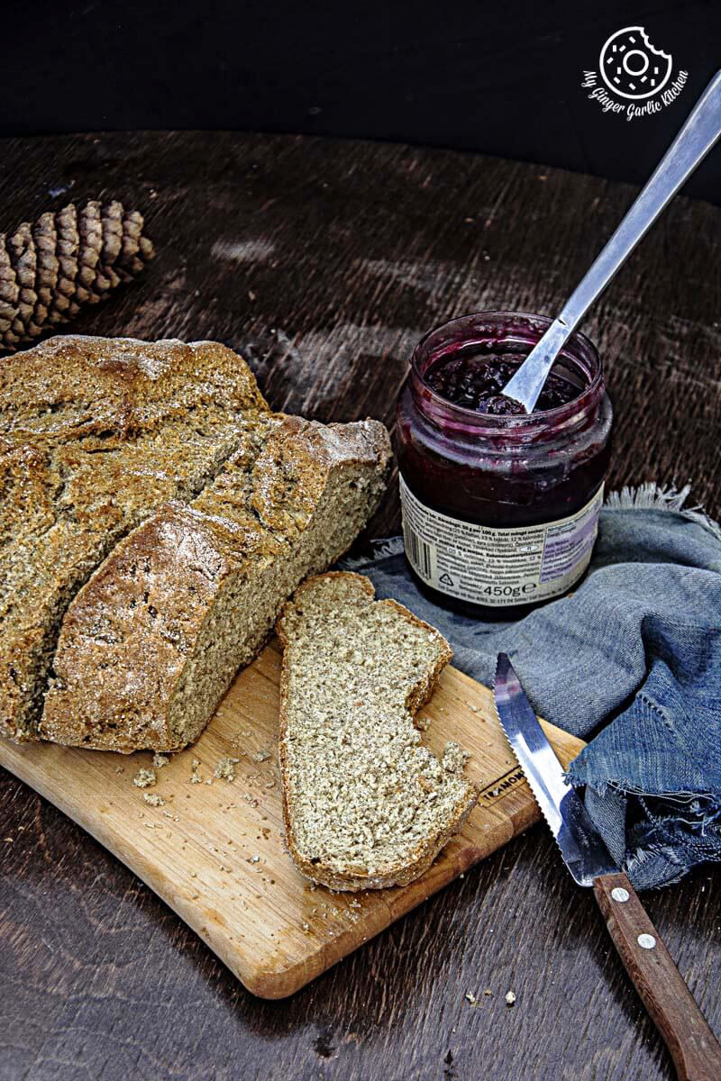 a loaf of rye irish soda bread on a cutting board with a jam jar and a knife in it