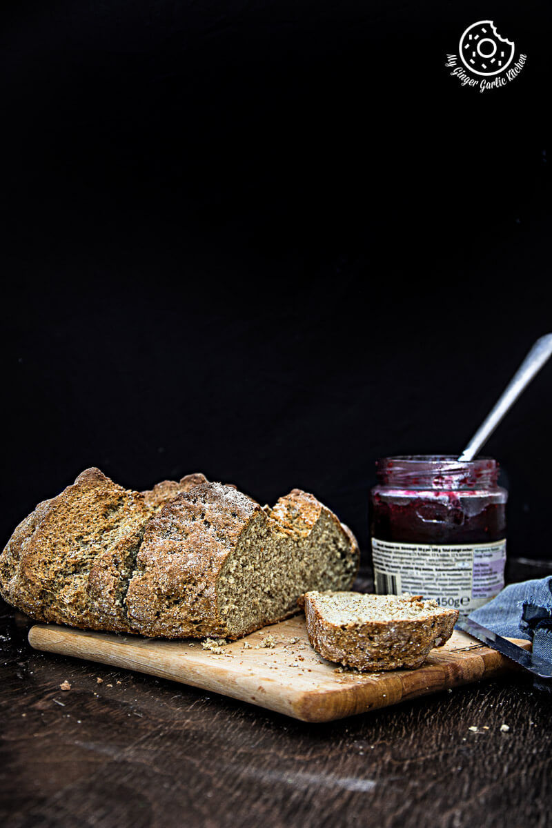 a loaf of rye irish soda bread on a cutting board with a jar of jam