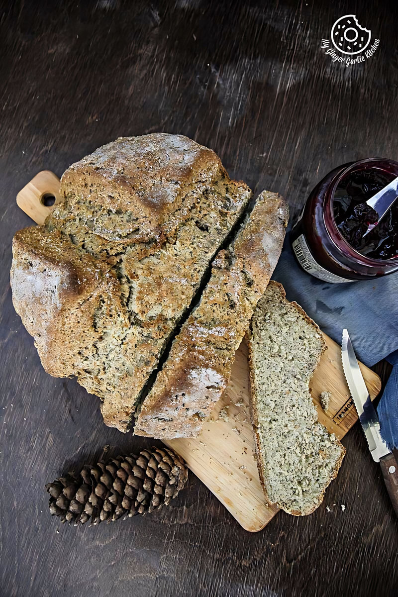 a loaf of rye irish soda bread on a cutting board with a knife and pine cone