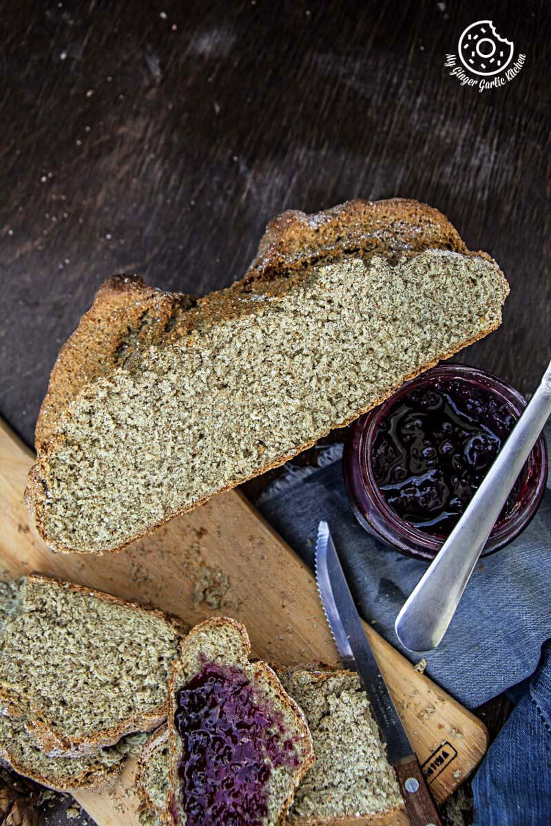 a loaf of rye irish soda bread with a knife and a bowl of jam