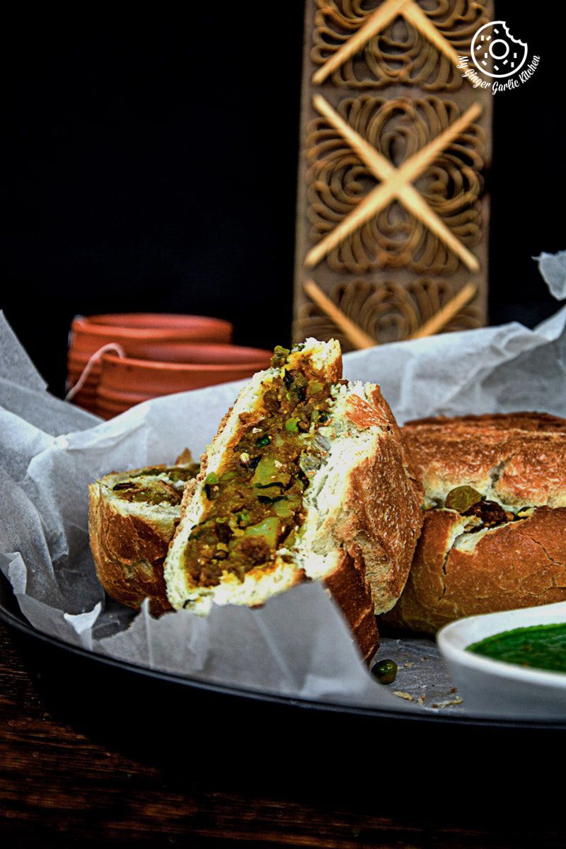 a samosa french loaf with a side of green chutney on a plate