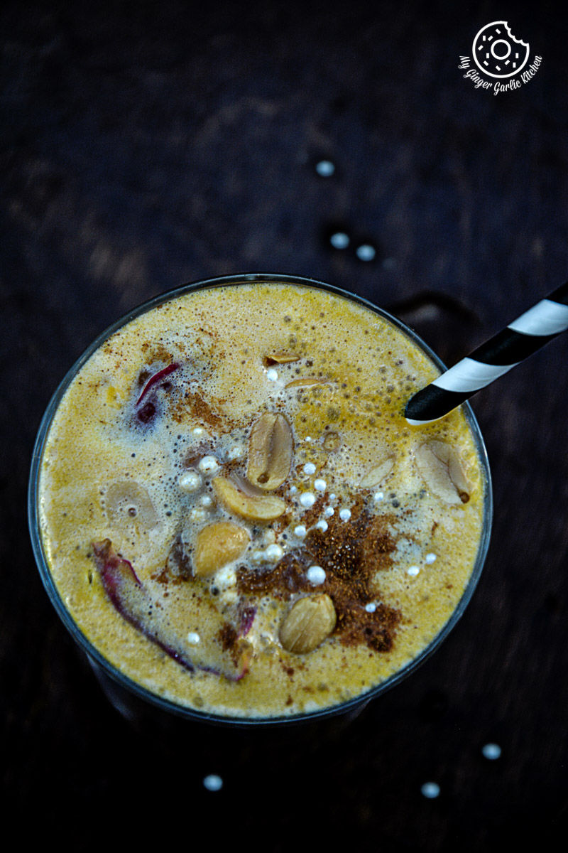 a glass of a spiced chai pumpkin smoothie with a spoon and a spoon sticking out of it