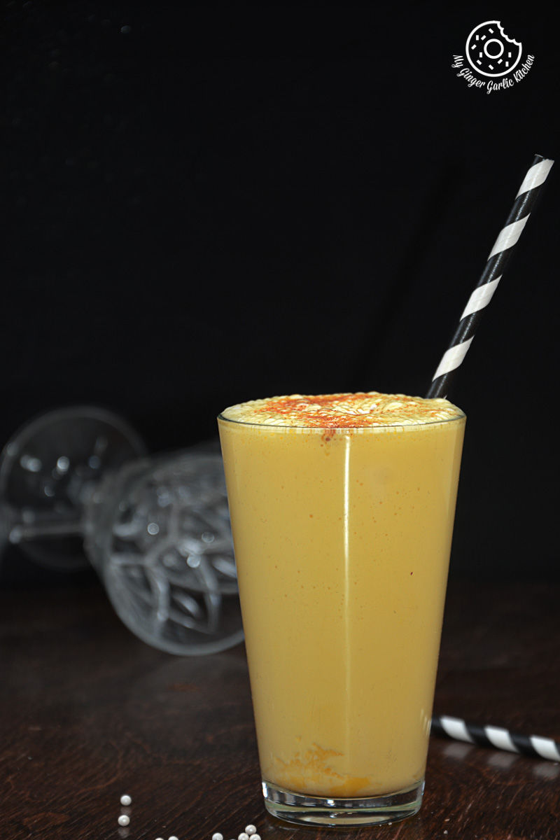 a glass of a spiced chai pumpkin smoothie with a straw and a striped straw
