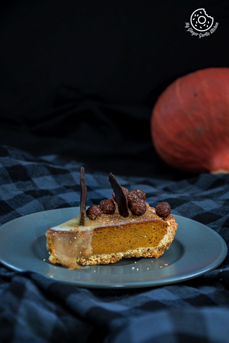 a piece of spiced pumpkin pie on a plate with a pumpkin in the background