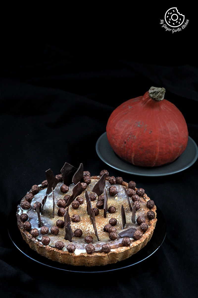 a spiced pumpkin pie with chocolate and candy on it on a plate
