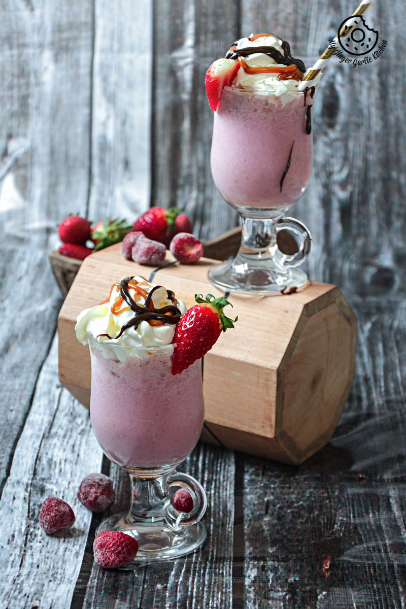 two glasses of strawberry cake shake with whipped cream and strawberries