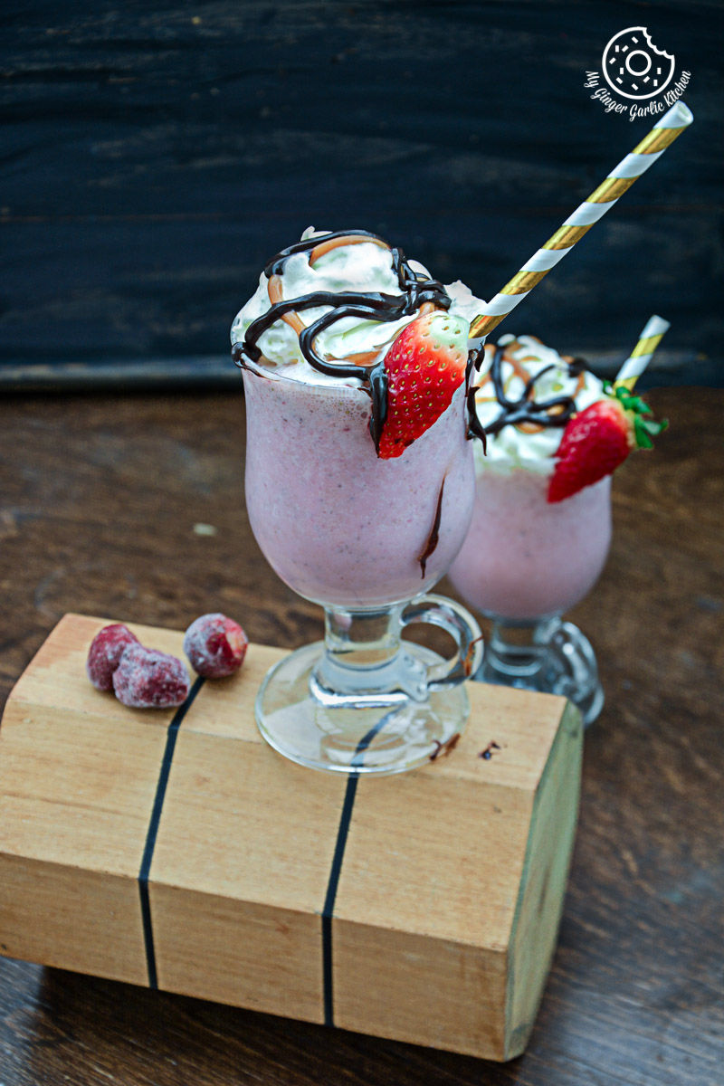 two glasses of strawberry cake shake with strawberries and chocolate
