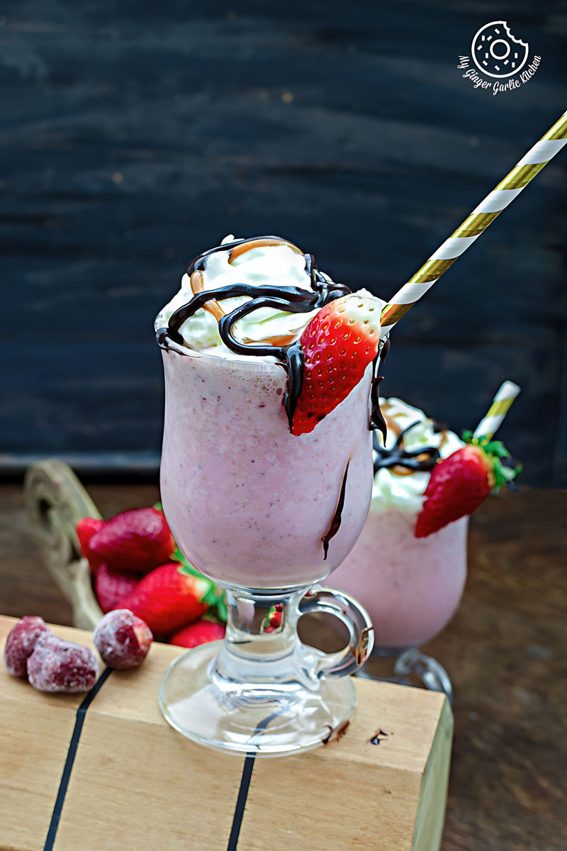 a glass of strawberry cake shake with strawberries and chocolate sauce