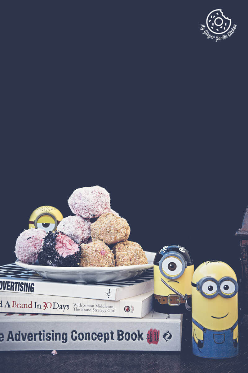 a plate with strawberry cheesecake bites three minion figurines sitting on a table with books