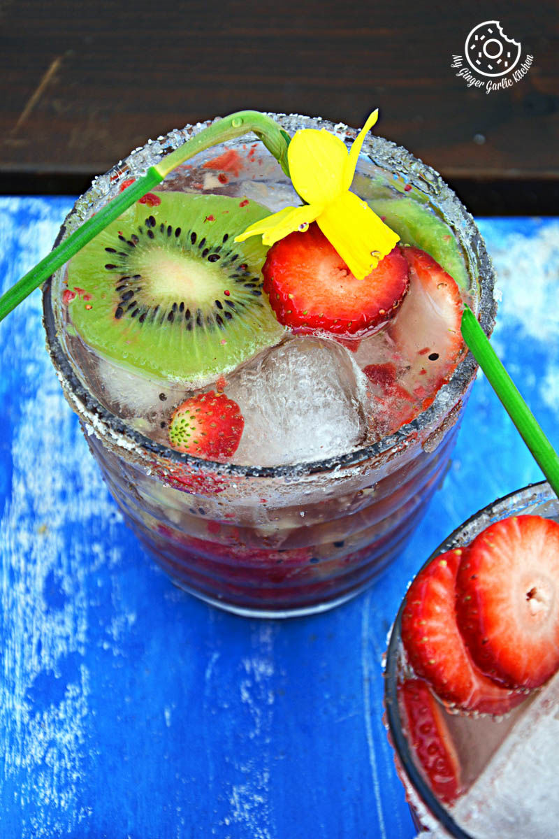 a glass of strawberry kiwi sparkling cooler with ice and a flower