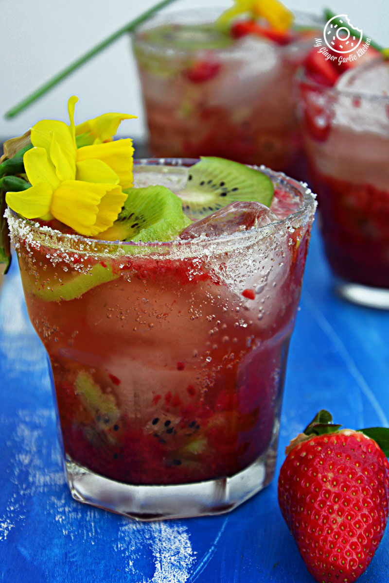 two glasses of strawberry kiwi sparkling cooler with a strawberries and a flower