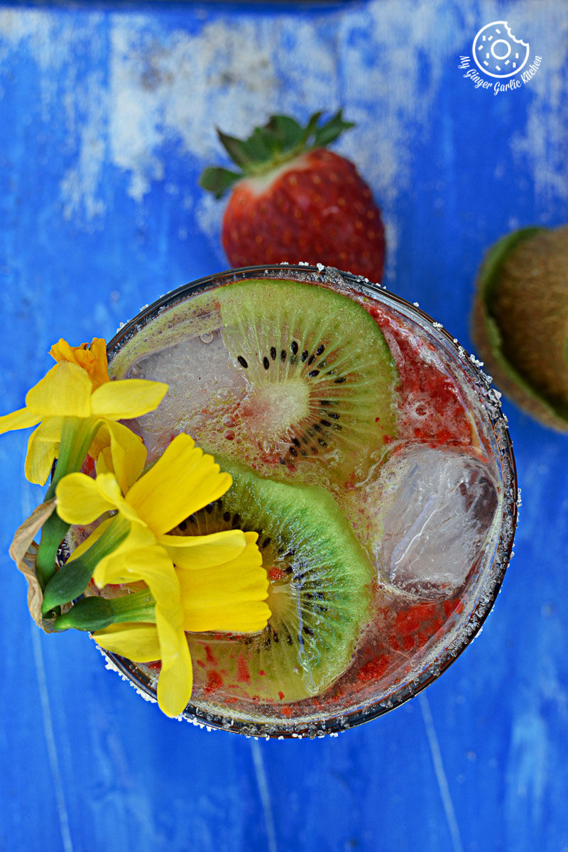 a glass with a strawberry kiwi sparkling cooler in it