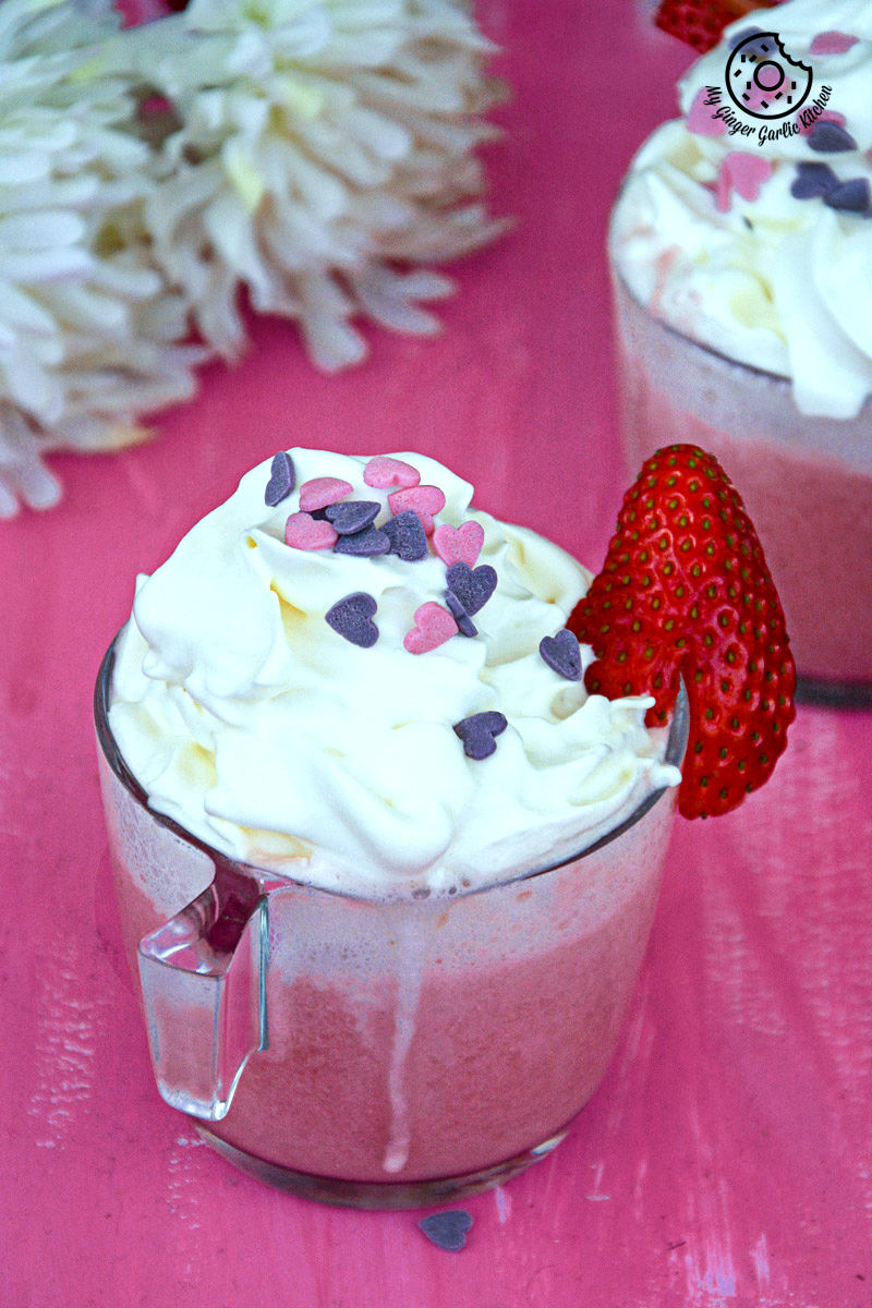 two cups of strawberry white hot chocolate with whipped cream and strawberries