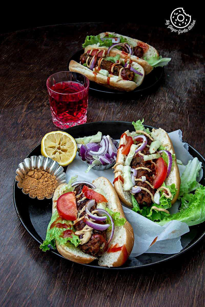 two sweet potato cabbage hot dogs on a plate on a table with a glass of juice