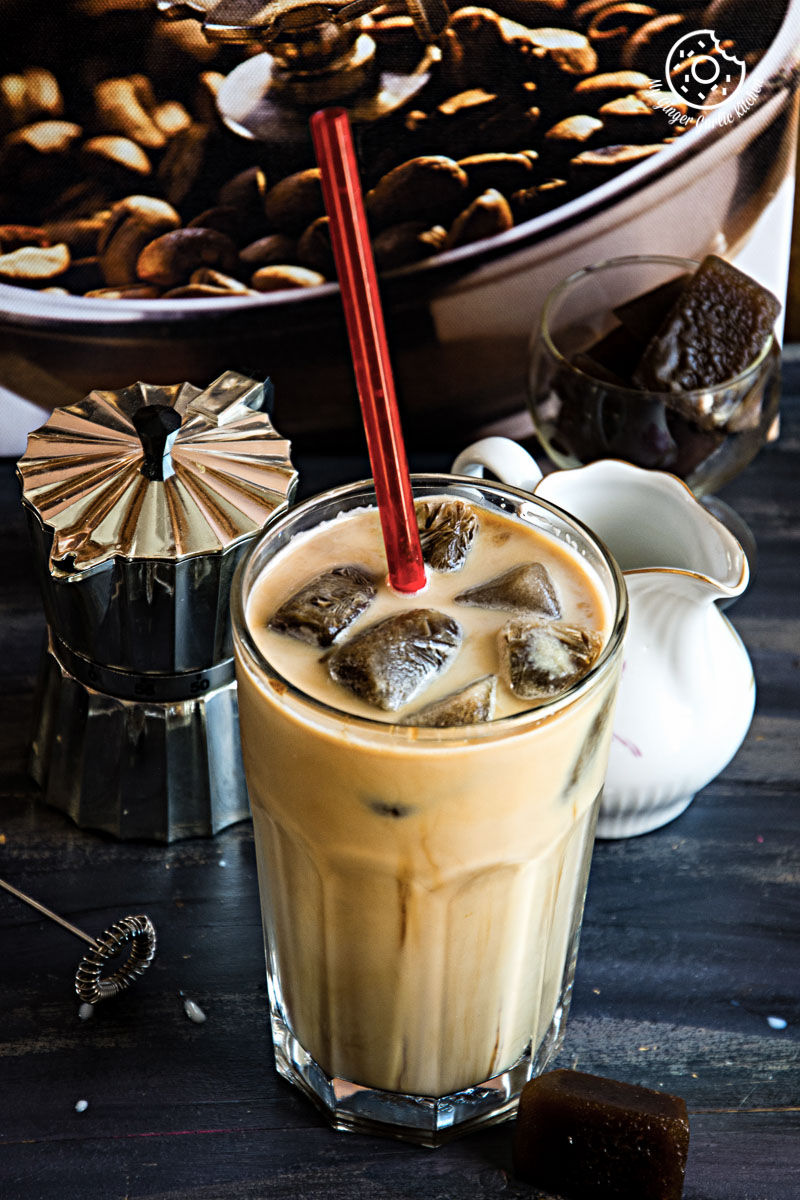 a glass of vanilla iced mocha with coffee ice cubes with a red straw