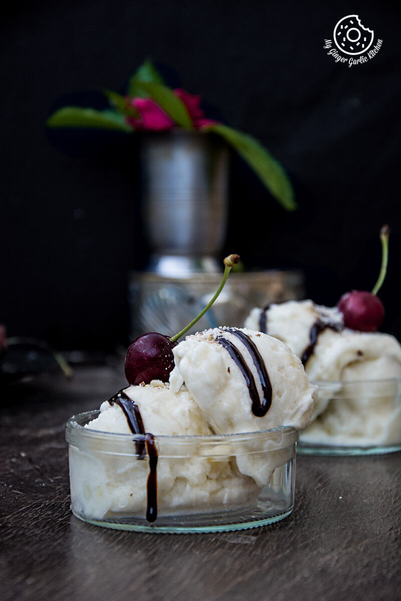 two bowls of vegan honeydew melon banana ice cream with chocolate sauce and cherries on top