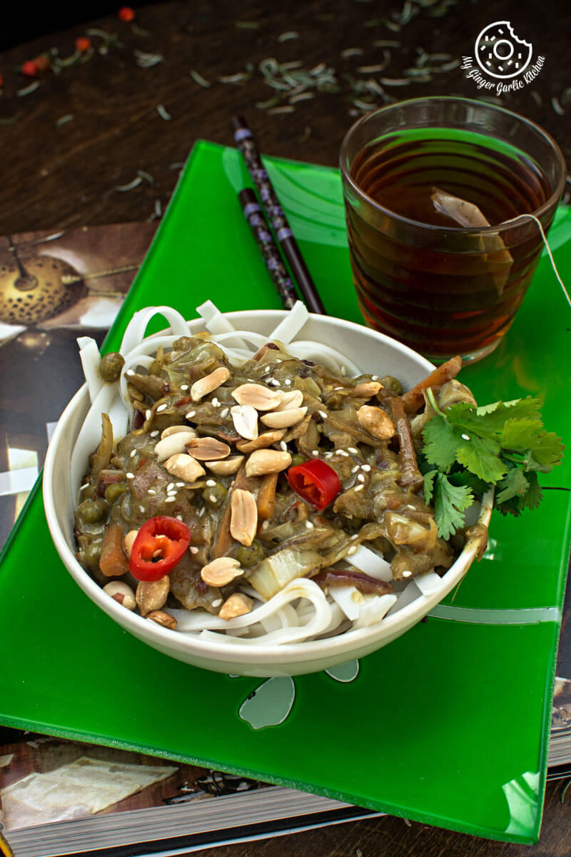 a bowl of vegan Thai green curry vegetable noodles on a green place mat