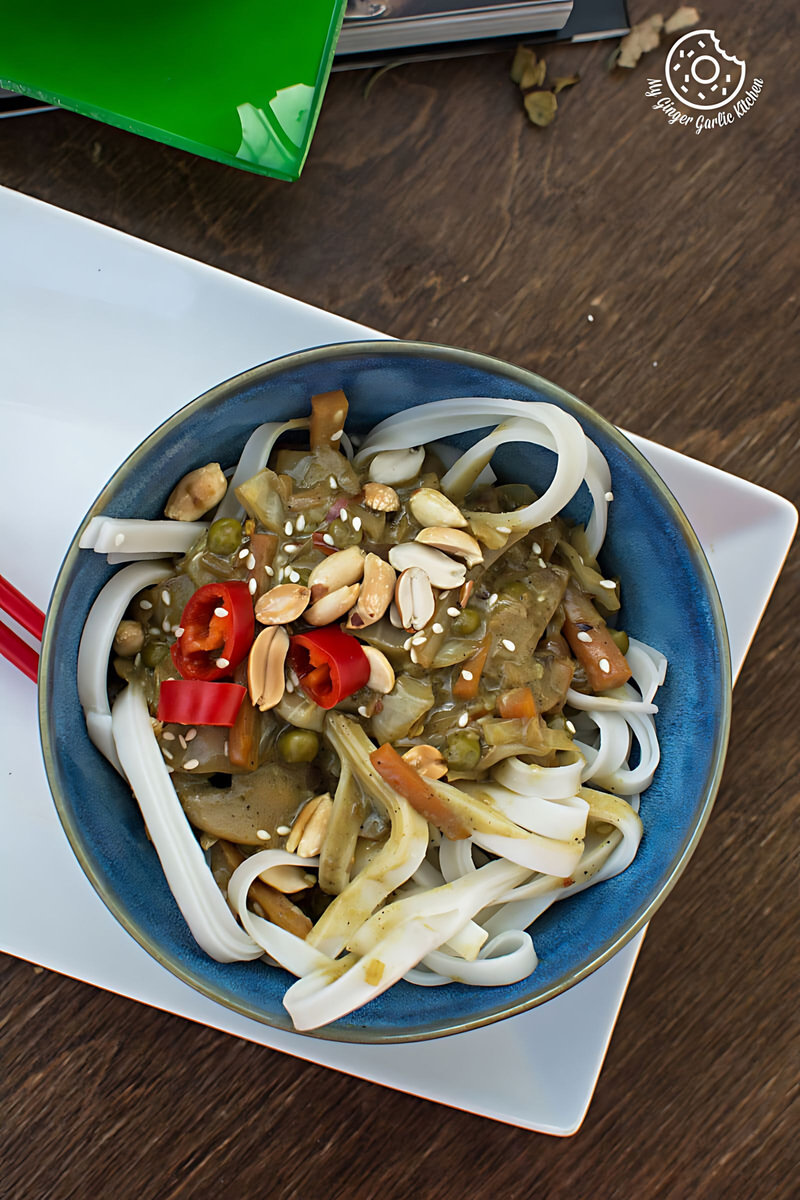 a bowl of vegan Thai green curry vegetable noodles with noodles and vegetables on a plate