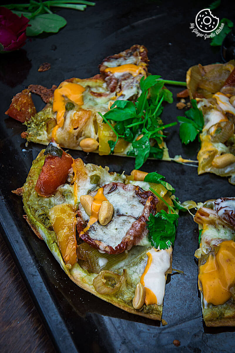 four pieces of a veggie tortizza or tortilla pizza on a black tray with a flower