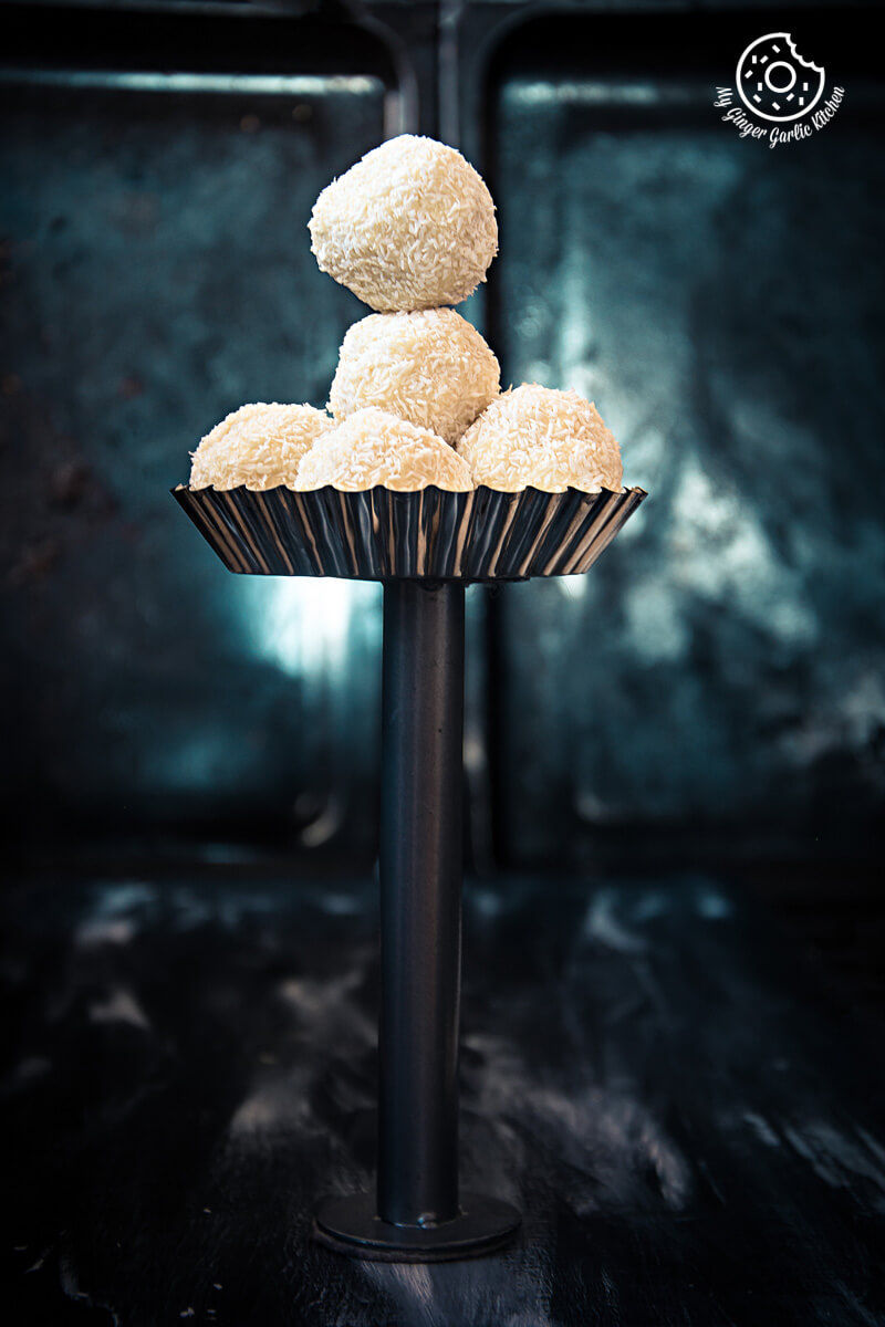 five white chocolate coconut truffles stacked on top of each other in a cup