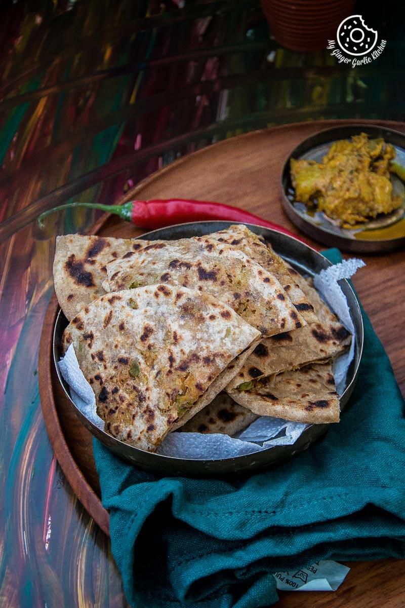 a bowl of patta gobi paratha pieces that is on a table with a bowl of pickle