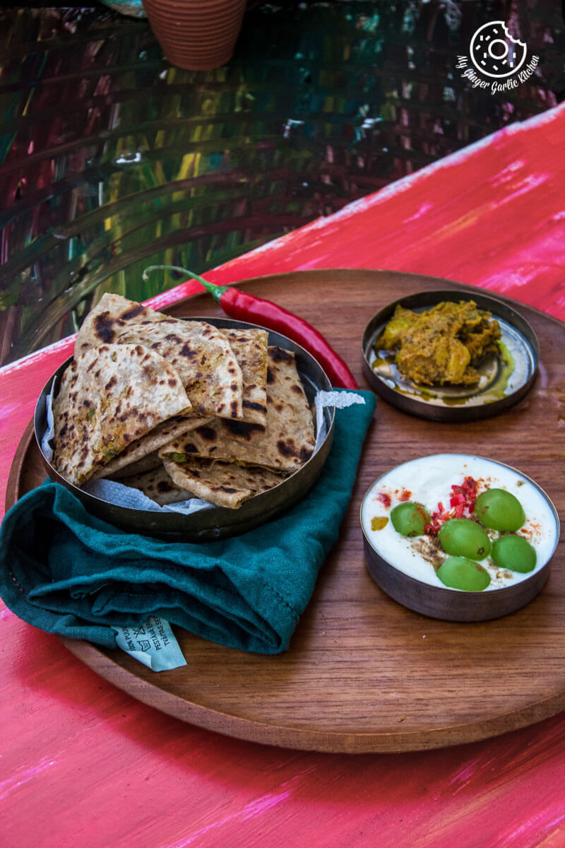 a plate of cabbage peas stuffed paratha or patta gobi ka paratha on a table with a bowl of dip