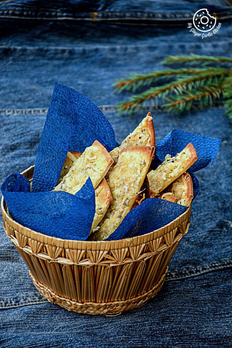 a basket of a stack of cheesy garlic pizza sticks in a blue cloth