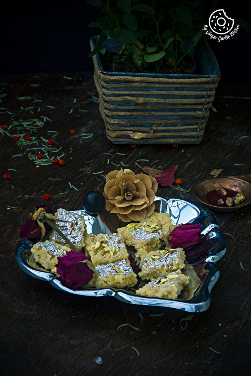 a plate of kopra pak or nariyal ki burfi on a table with dried flowers